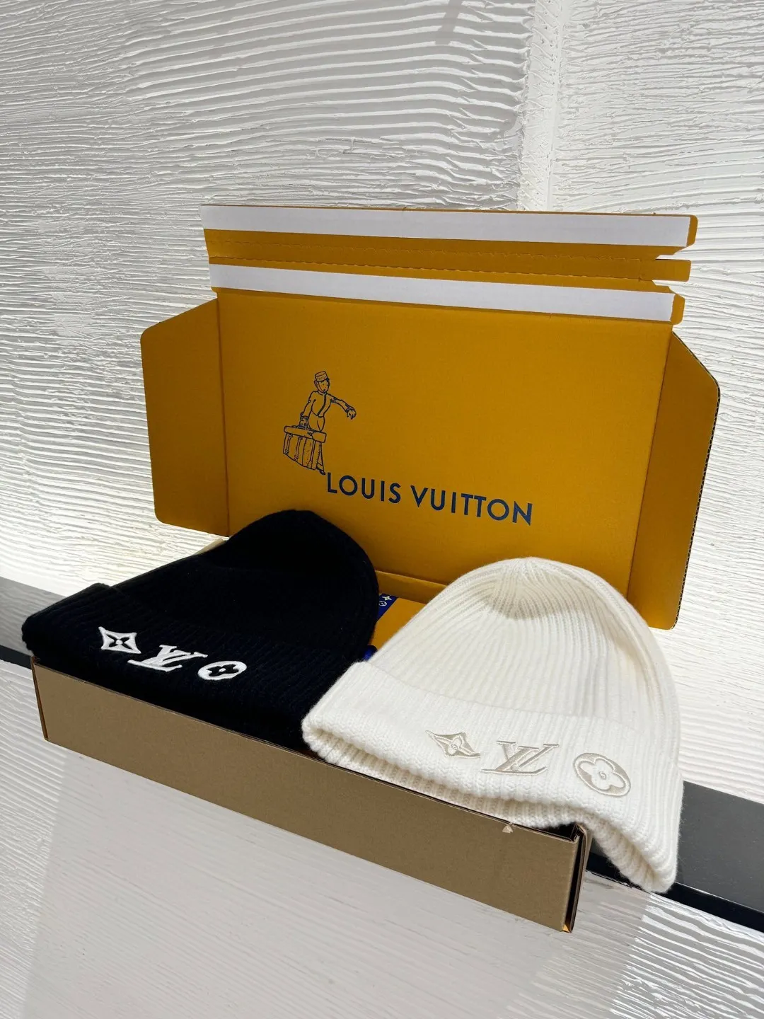 LOUIS VUITTON new embroidered wool cold hat ●Original version: 3800 purchase and development ●Item number: 1681973-A45 ●Fabric: wool blended fabric ●Technology: embroidery production ●Color: white/black ●Version: fitted version ●Description: This is LV The 2025 autumn and winter series logo embroidered knitted cold hat is made of 100% Italian virgin wool, woven with a 30-needle dense weaving process. The yarn twist reaches 600 twists/meter, which has both warmth and stiffness. The main body of the hat has a vertical grooved texture, which is elastically wrapped through fixed-spacing stitching techniques. The front logo of the hat uses three-dimensional appliqué technology, and the Monogram elements (quatrefoil, LV letters) are sewn with high-density embroidery threads of the same color. The edges are overlocked to prevent fuzzing and threading; the top of the hat is made of double-layer ribbing, which is durable and elastic and fits the ears. The finished product is shaped by high-temperature steam, and the three-dimensional shape of the hat is not easily deformed. The post-finishing process includes anti-static treatment, making it more comfortable for daily wear. The lining of the packaging is printed with the brand's classic "luggage maker" pattern, continuing the brand's retro luxury tone. The overall wiring is straight and delicate, the fabric is comfortable and soft, and the color is consistent without color difference. It can be matched with the same style to create a fashionable look and control various occasions. Customized accessories, complete with three standards, same style for men and women!